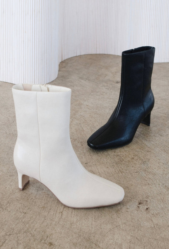 White and black ankle boots on a textured surface with a white background