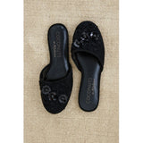 Black embroidered slippers with 'Coconuts by Matisse' branding on a beige carpet.