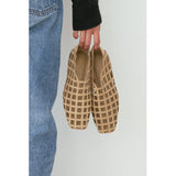 Person holding a pair of cage-style flat shoes against a plain background.