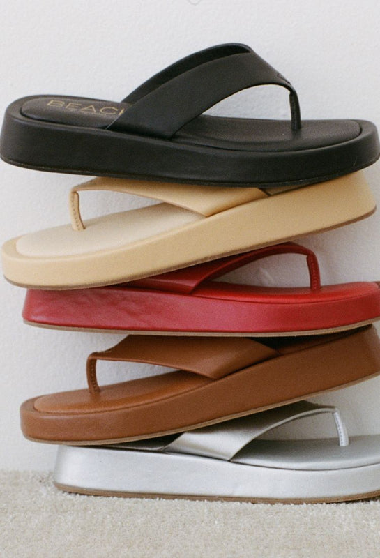Stack of multicolored flip-flop sandals on a light background.