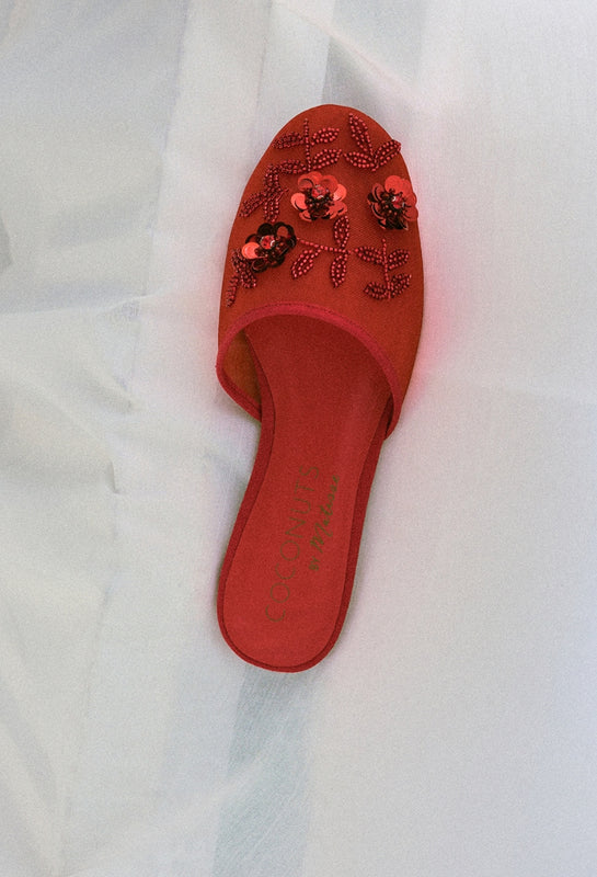 Red sandal with floral embellishments on a white background