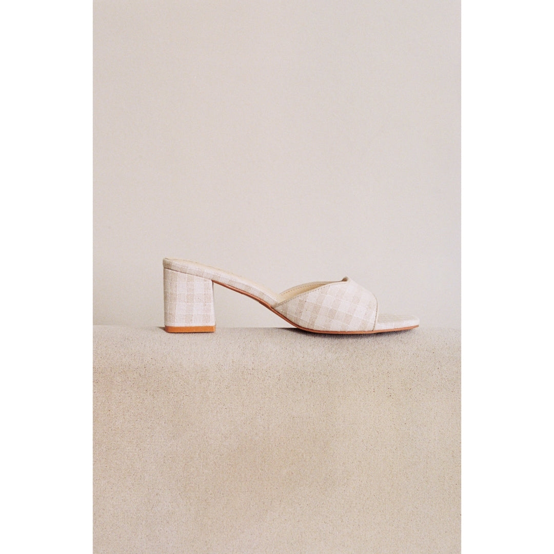 White high-heeled shoe on a beige surface with a neutral background.