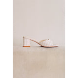 White high-heeled shoe on a beige surface with a neutral background.
