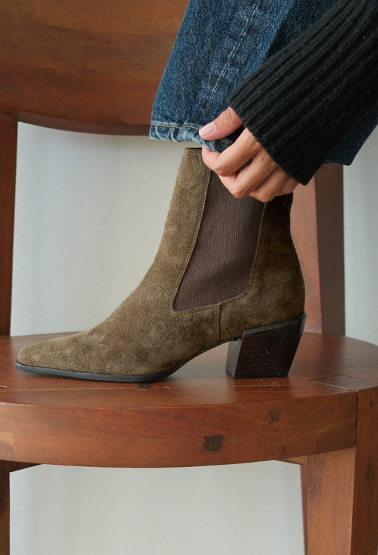 Brown suede ankle boot being worn on a wooden chair