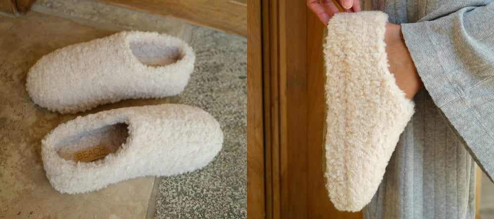 Pair of fluffy slippers on a textured surface with a person wearing one of them.