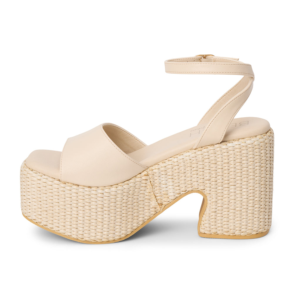 Ivory faux leather platform sandal with wide front strap, adjustable ankle strap, chunky woven platform heel, and open toe, shown on a white background.