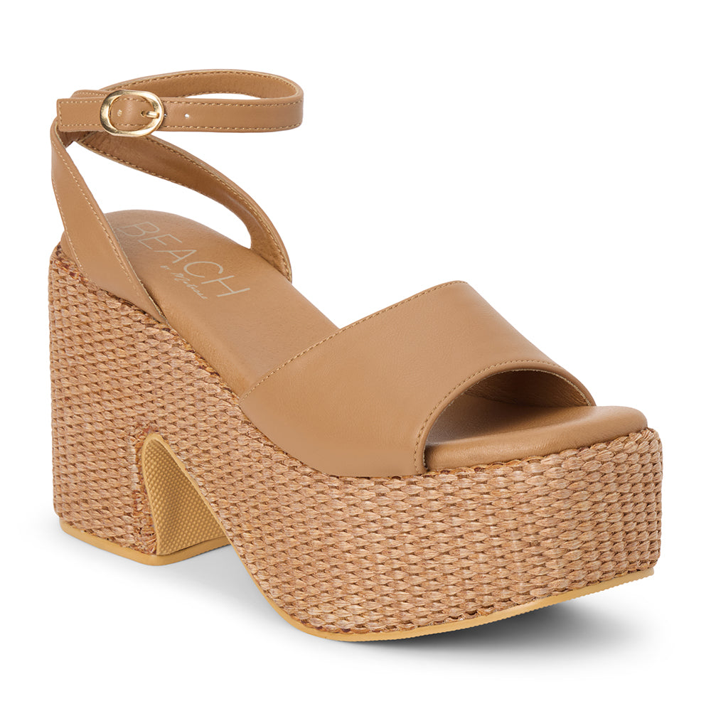 Cognac faux leather platform sandal with wide front strap, adjustable ankle strap, chunky woven platform heel, and open toe, shown on a white background.