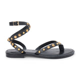 Black leather thong sandal with gold studs and wraparound ankle strap shown on a white background.