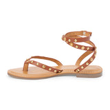Brown leather thong sandal with gold studs and wraparound ankle strap shown on a white background.