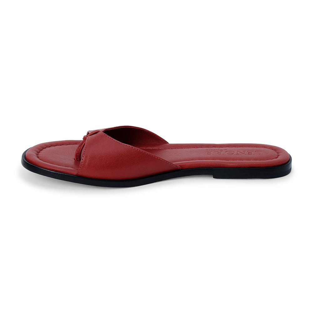 Cherry red leather flat sandal with minimalist thong strap and padded footbed, shown on a white background.