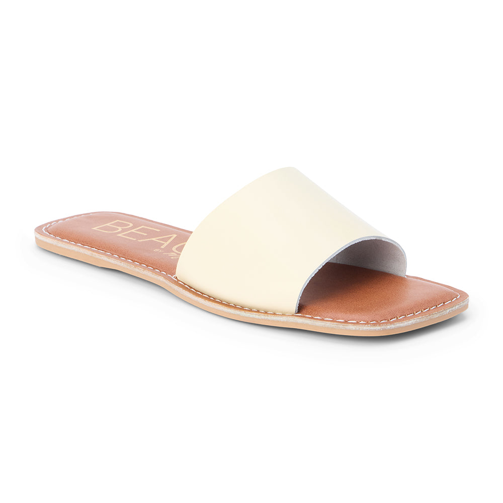 Light yellow leather slide sandal with a wide single strap and flat sole, shown on a white background.