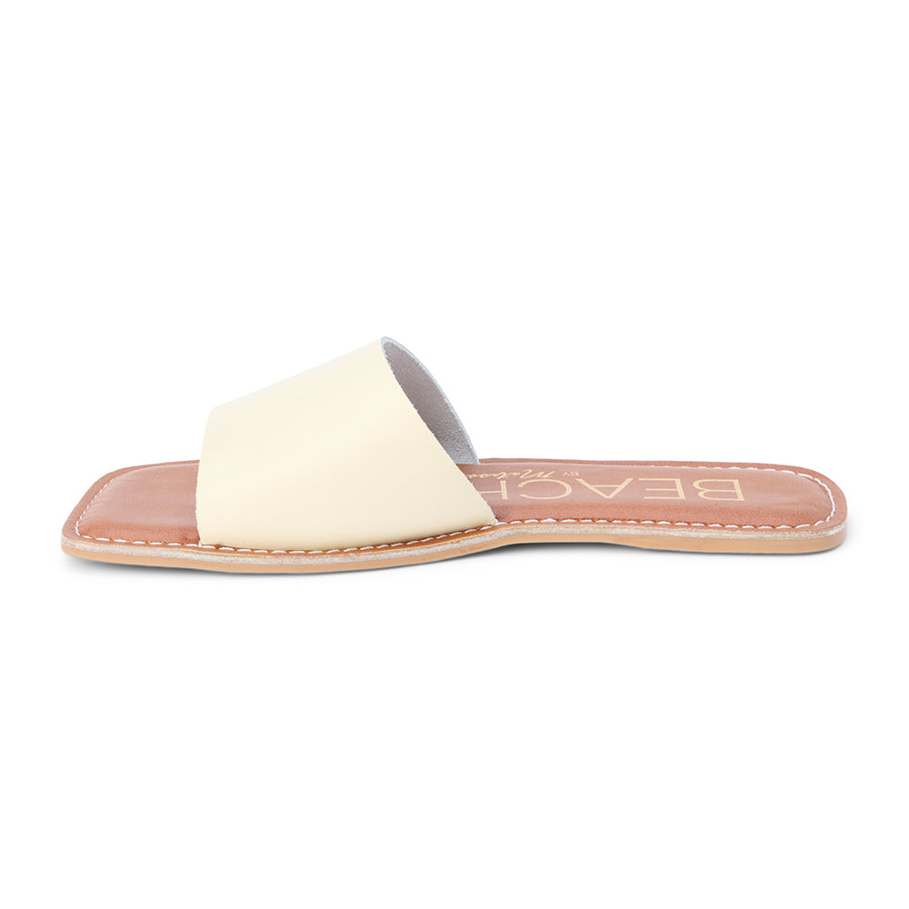 Light yellow leather slide sandal with a wide single strap and flat sole, shown on a white background.