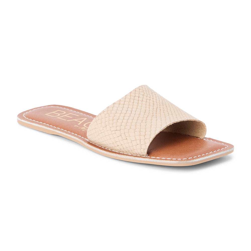 Tan suede slide sandal with a wide single strap and flat sole, shown on a white background.