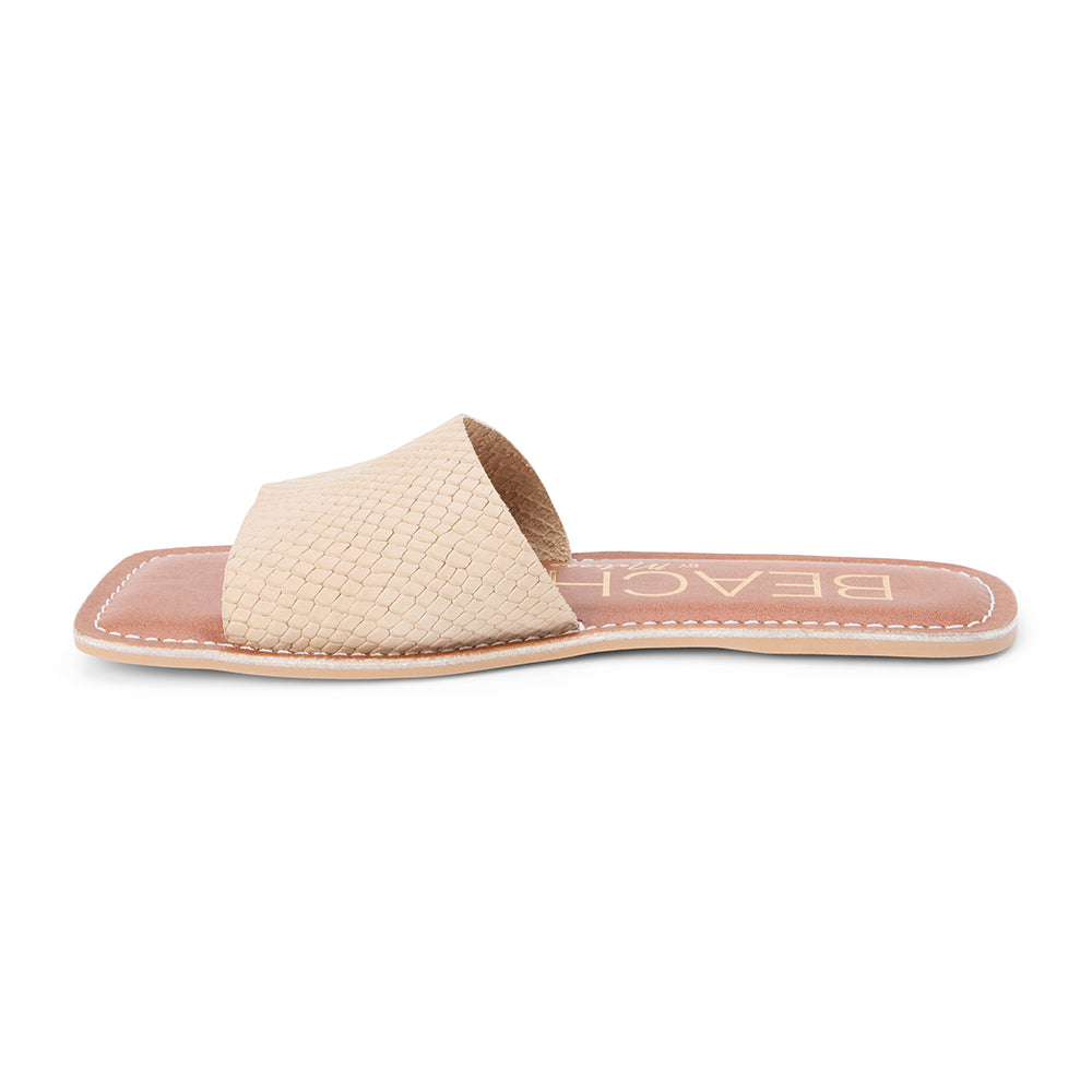 Tan suede slide sandal with a wide single strap and flat sole, shown on a white background.