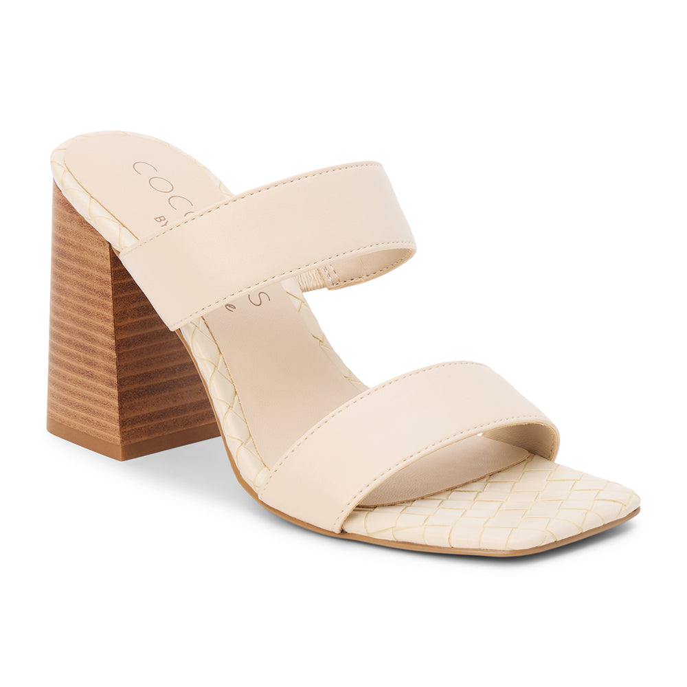Beige faux leather heeled sandal with wide straps, woven footbed, and tall block heel, shown on a white background.