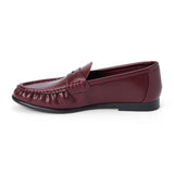 Vegan burgundy faux leather penny loafer with a penny strap, moc-toe stitching, gathered toe detail, and black low heel shown on a white background.