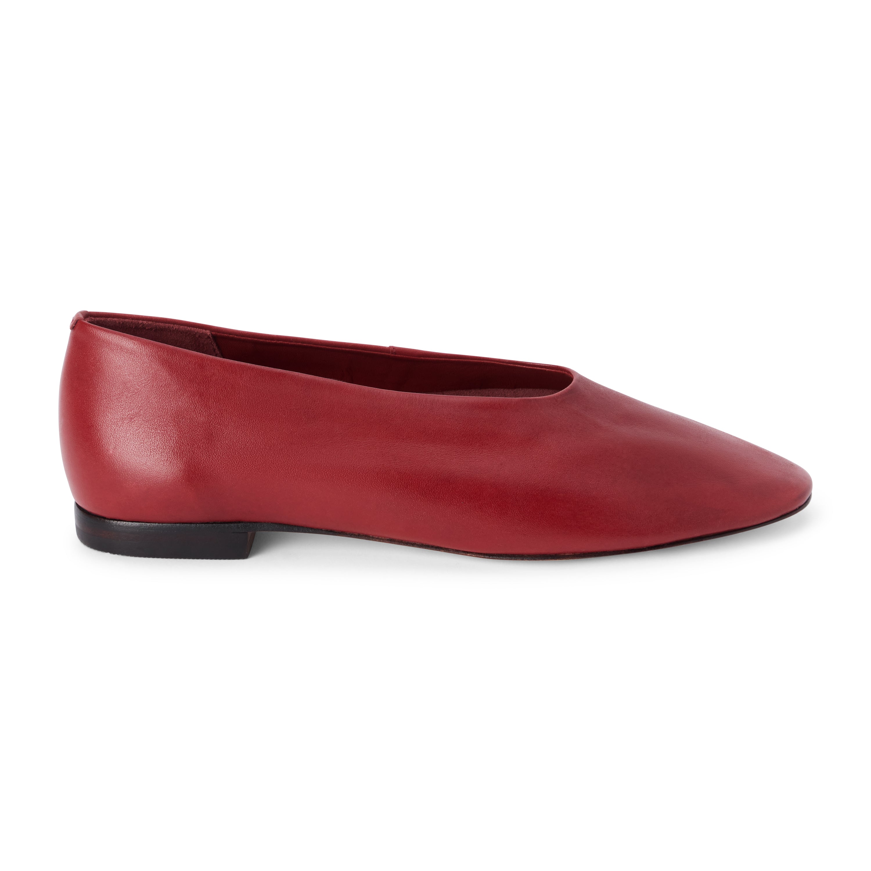 Red leather flat with a softly squared toe, high-cut vamp, smooth upper, and low dark heel shown on a white background.