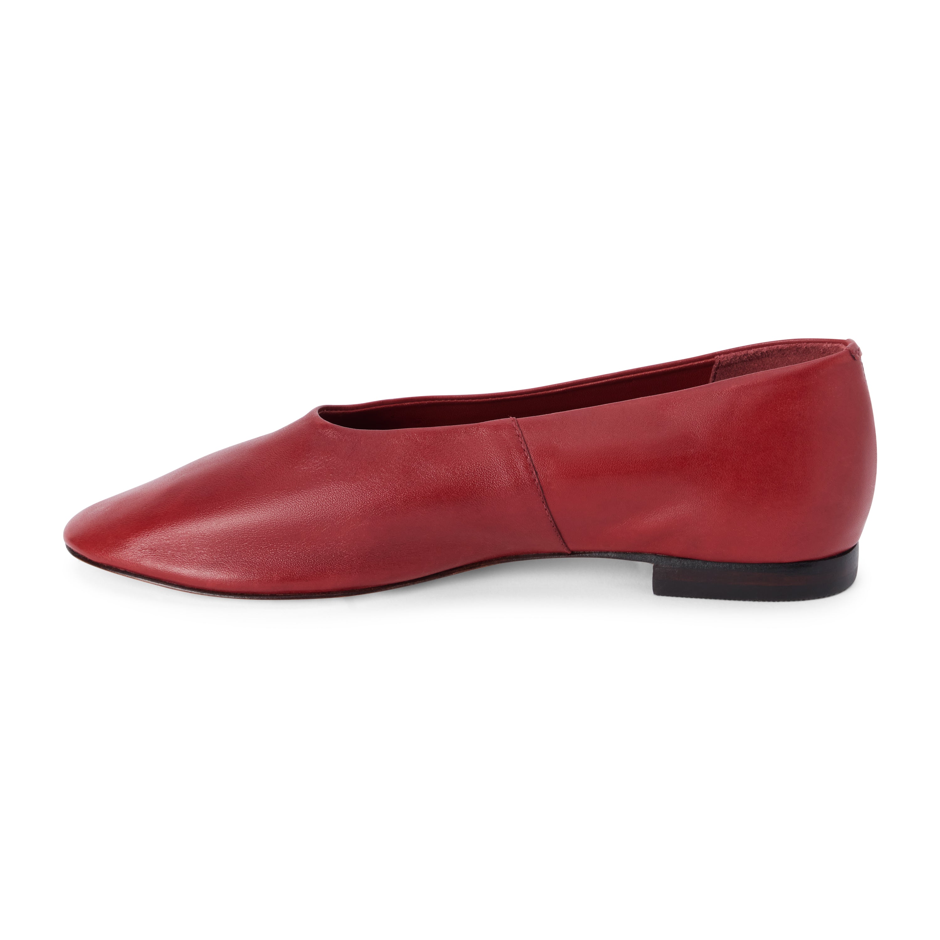 Red leather flat with a softly squared toe, high-cut vamp, smooth upper, and low dark heel shown on a white background.