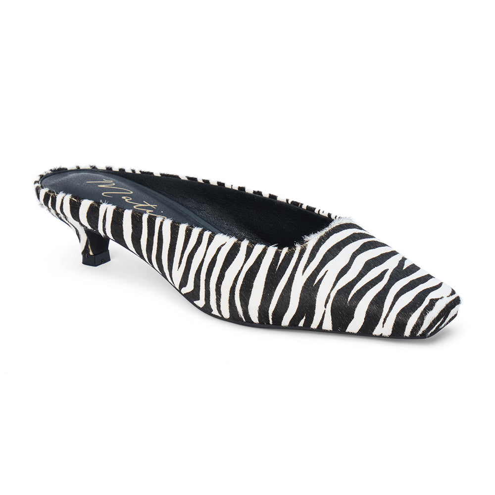 Ivory and black zebra-print cow hair heeled mule with a pointed toe and low kitten heel shown on a white background.