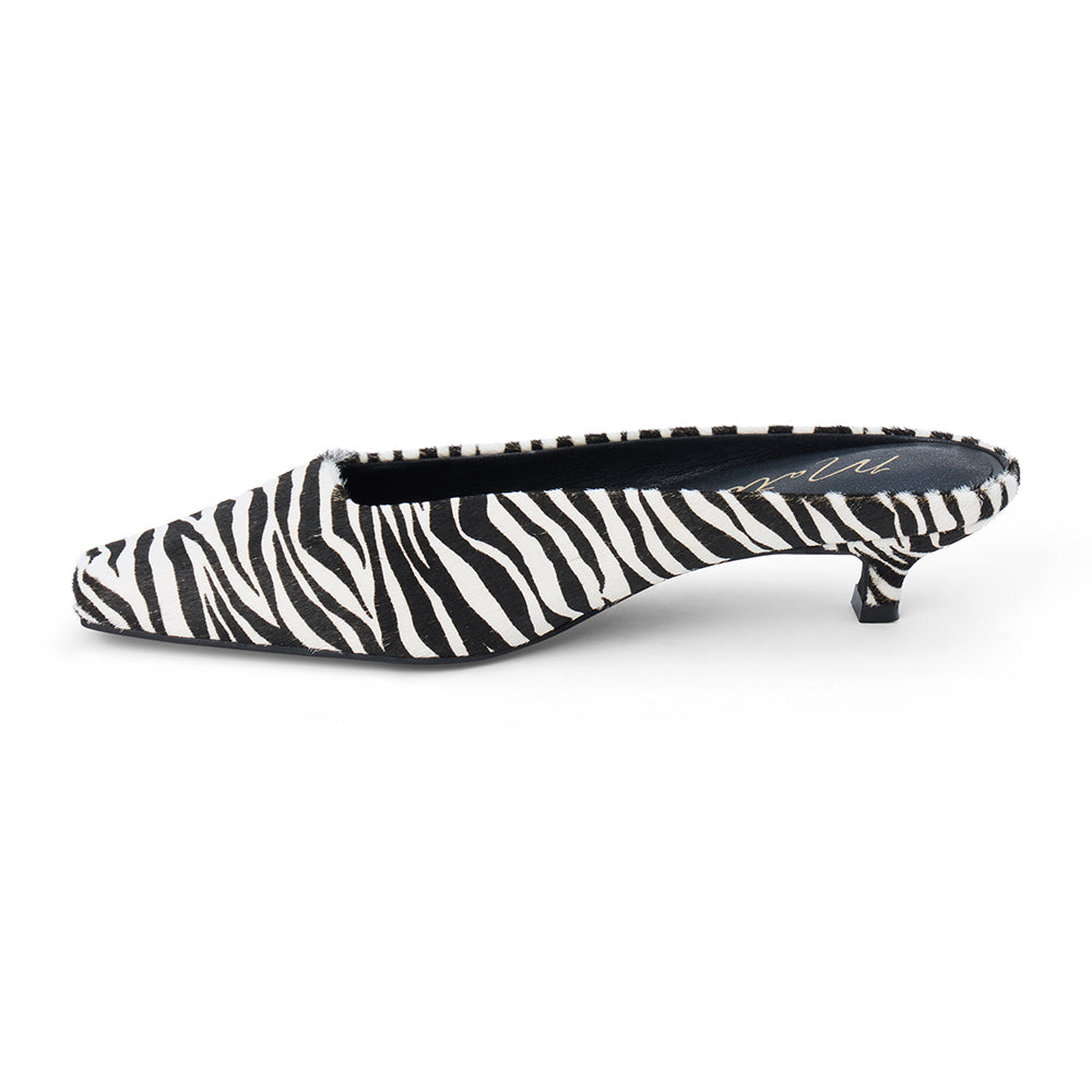 Ivory and black zebra-print cow hair heeled mule with a pointed toe and low kitten heel shown on a white background.