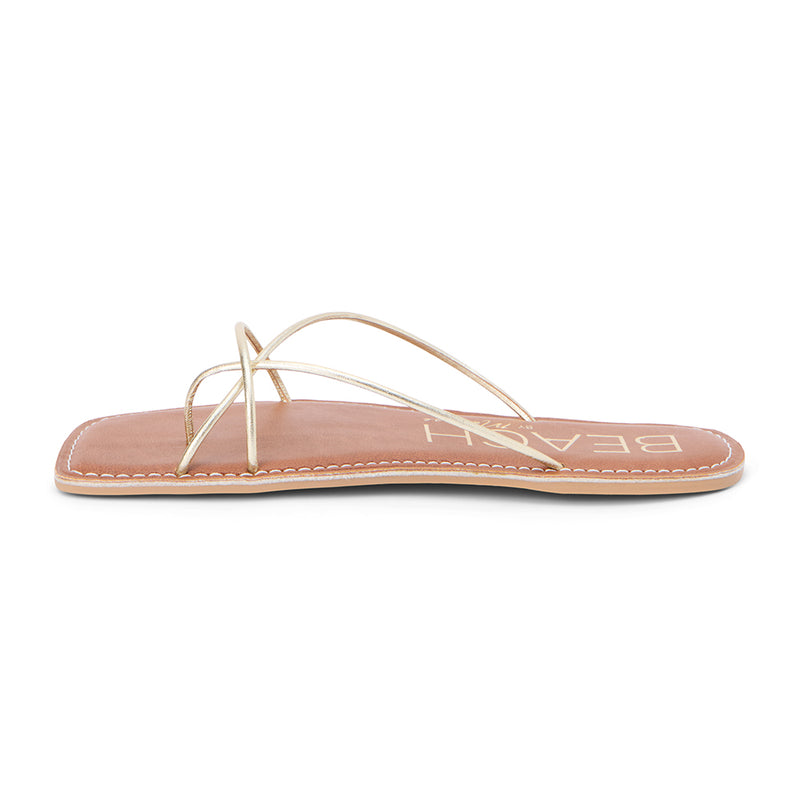 Coastline Strappy Sandal – Beach By Matisse – Gold minimalist flat sandals with delicate tubular straps, a square toe, and tan footbed. A barely-there silhouette that brings effortless polish to warm-weather dressing.