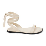 Ivory leather flat sandal with delicate straps and a secure ankle tie. A minimalist and feminine silhouette, perfect for effortless warm-weather styling.