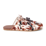 Brown and white cow hair mule with a lace-up front, stitched detailing, flat sole, and open back, shown in side profile on a white background.