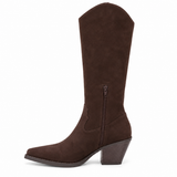 Vegan brown faux suede knee-high Western boot with long side fringe, a pointed toe, curved shaft opening, and stacked block heel shown on a white background.
