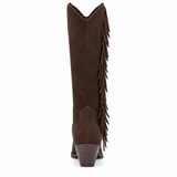 Vegan brown faux suede knee-high Western boot with long side fringe, a pointed toe, curved shaft opening, and stacked block heel shown on a white background.
