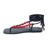 Black thong sandal with braided ankle wrap straps and red bead accents shown on a white background.