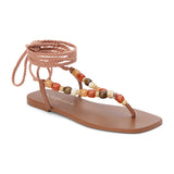 Tan thong sandal with braided ankle wrap straps and multicolor bead accents shown on a white background.