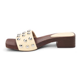 Light yellow vegan slide sandal with silver stud accents and low block heel, shown on a white background.