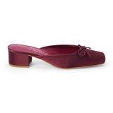 Vegan burgundy satin heeled mule with a square toe, tonal bow detail, open back, and low block heel shown on a white background.