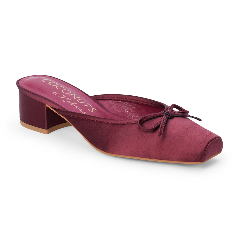 Vegan burgundy satin heeled mule with a square toe, tonal bow detail, open back, and low block heel shown on a white background.
