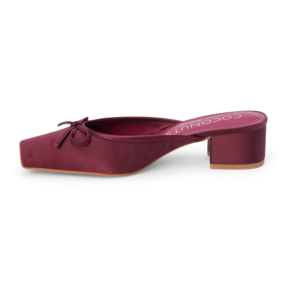 Vegan burgundy satin heeled mule with a square toe, tonal bow detail, open back, and low block heel shown on a white background.