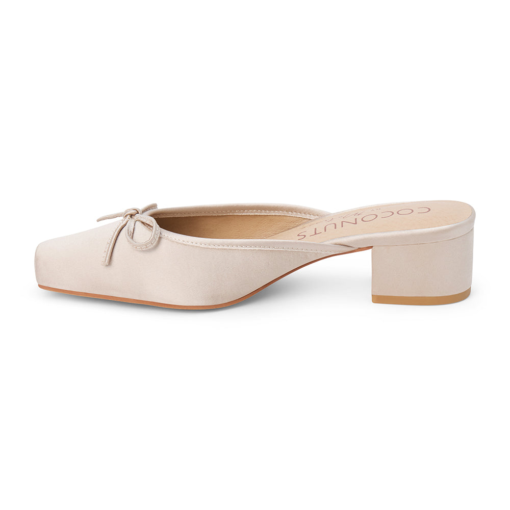 Vegan ivory satin heeled mule with a square toe, tonal bow detail, open back, and low block heel shown on a white background.