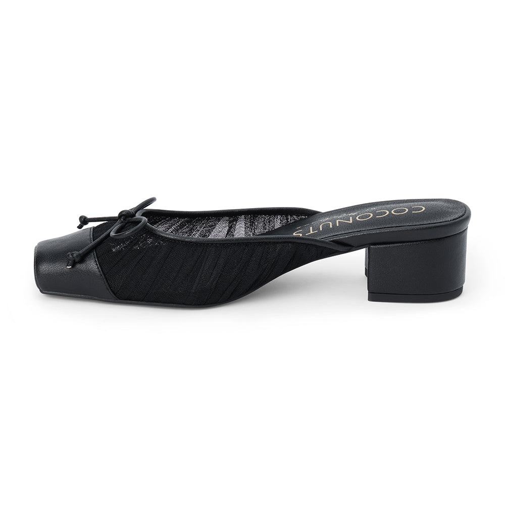 Vegan black mesh heeled mule with a square toe, tonal bow detail, solid toe cap, and low block heel shown on a white background.