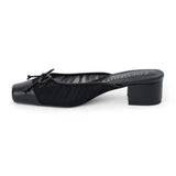 Vegan black mesh heeled mule with a square toe, tonal bow detail, solid toe cap, and low block heel shown on a white background.