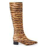 Tan cow hair knee-high boot with black zebra stripes, a pointed toe, tall shaft, and black low block heel shown on a white background.