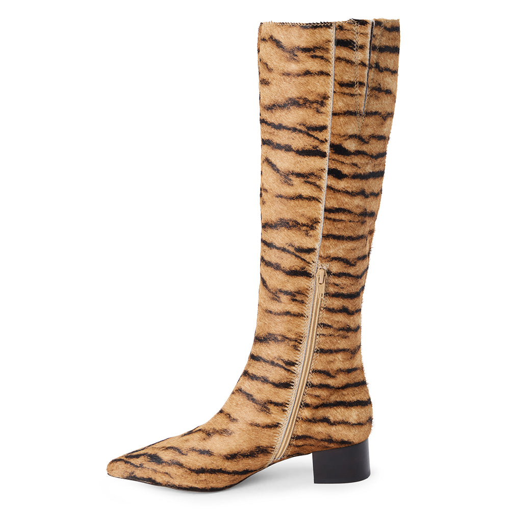 Tan cow hair knee-high boot with black zebra stripes, a pointed toe, tall shaft, and black low block heel shown on a white background.