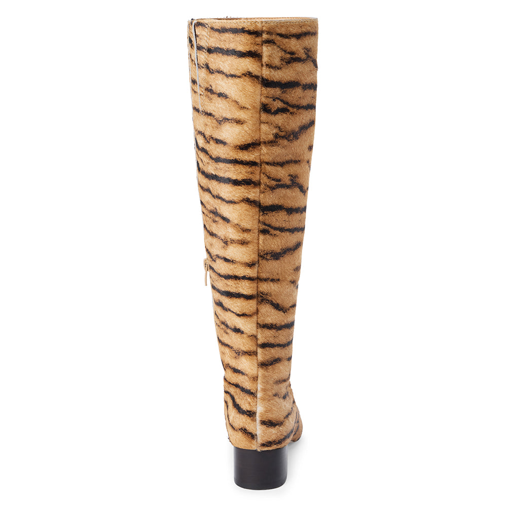 Tan cow hair knee-high boot with black zebra stripes, a pointed toe, tall shaft, and black low block heel shown on a white background.