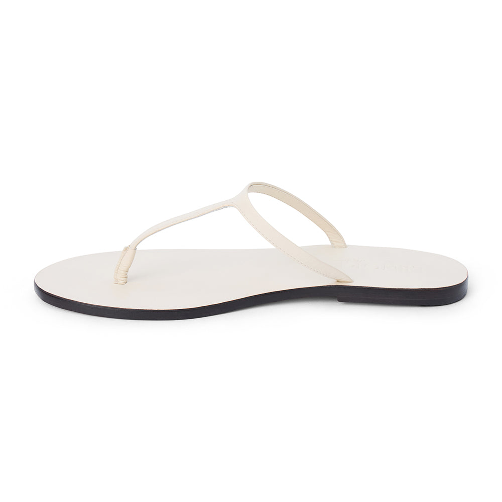 Ivory leather flat thong sandal with slim straps and minimalist design, shown on a white background.