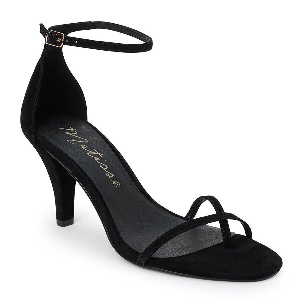Black suede heeled sandal with a toe loop, slim ankle strap, and tapered heel shown on a white background.