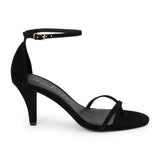 Black suede heeled sandal with a toe loop, slim ankle strap, and tapered heel shown on a white background.