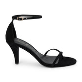 Black suede heeled sandal with a toe loop, slim ankle strap, and tapered heel shown on a white background.