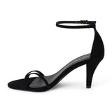 Black suede heeled sandal with a toe loop, slim ankle strap, and tapered heel shown on a white background.