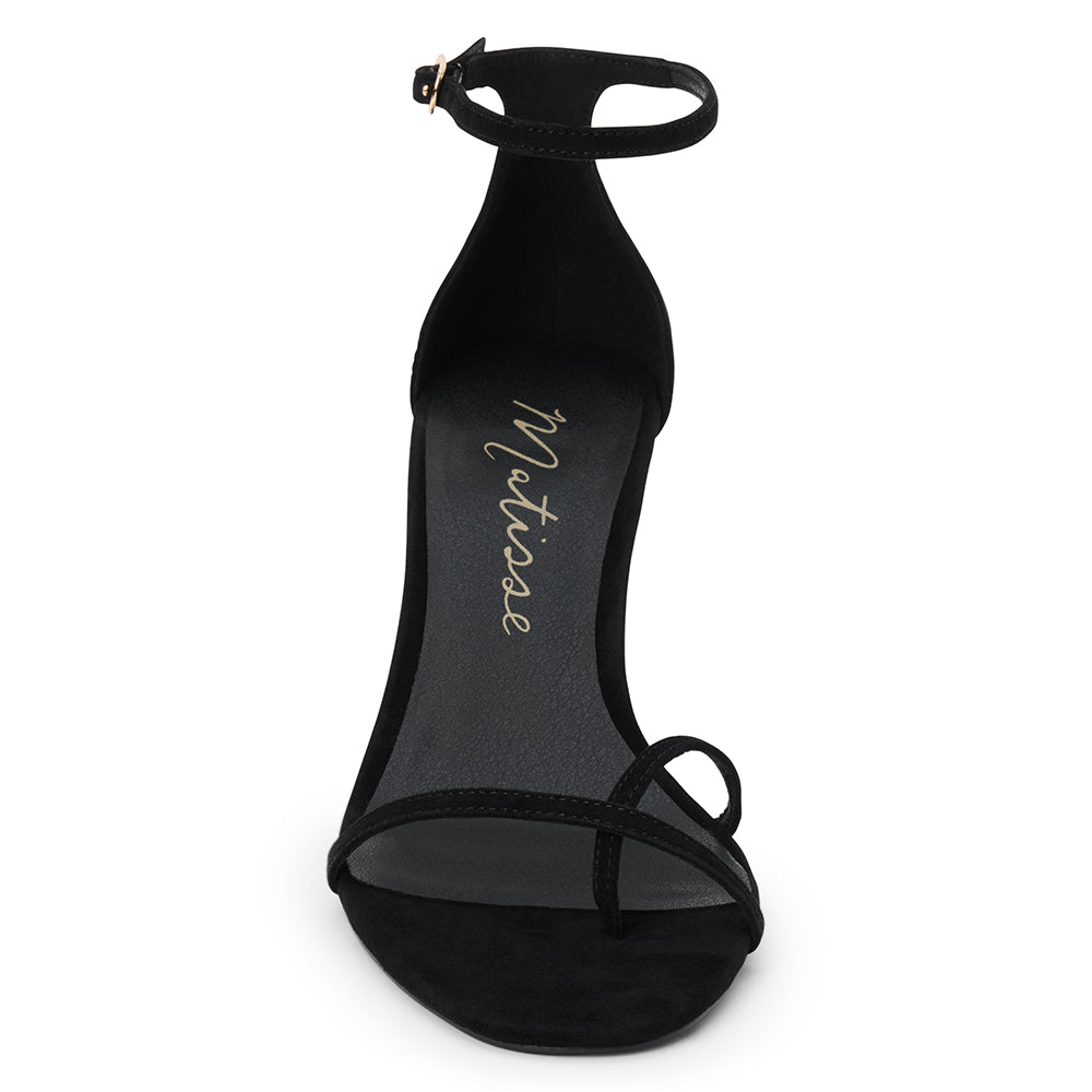 Black suede heeled sandal with a toe loop, slim ankle strap, and tapered heel shown on a white background.