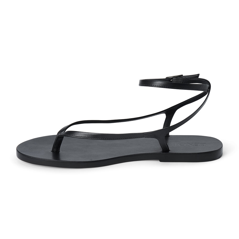 Black leather thong sandal with a minimalist strappy design and adjustable ankle buckle.