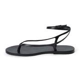 Black leather thong sandal with a minimalist strappy design and adjustable ankle buckle.
