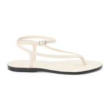 Ivory leather thong sandal with a minimalist strappy design and adjustable ankle buckle. A sleek and versatile style for effortless warm-weather dressing.